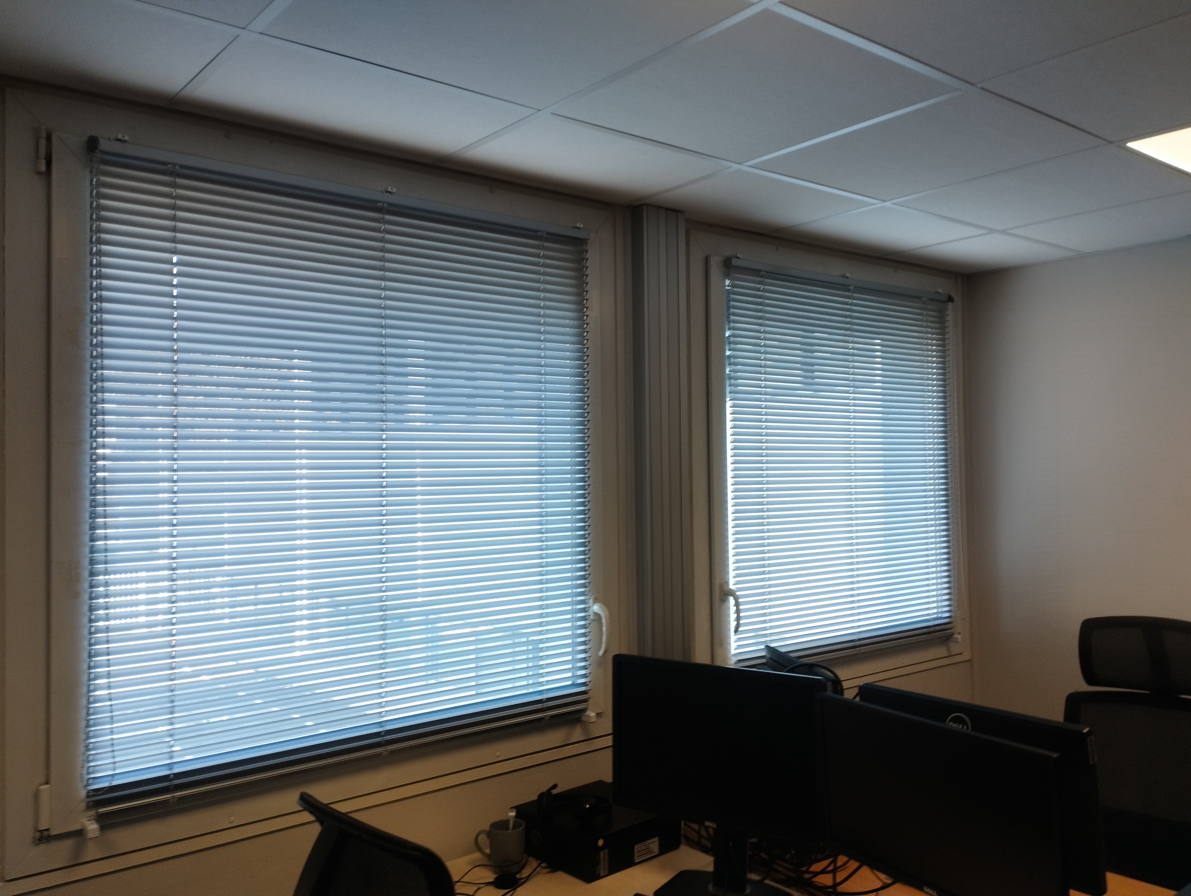 Stores vénitiens en aluminium installés dans un bureau professionnel, gestion de la lumière naturelle