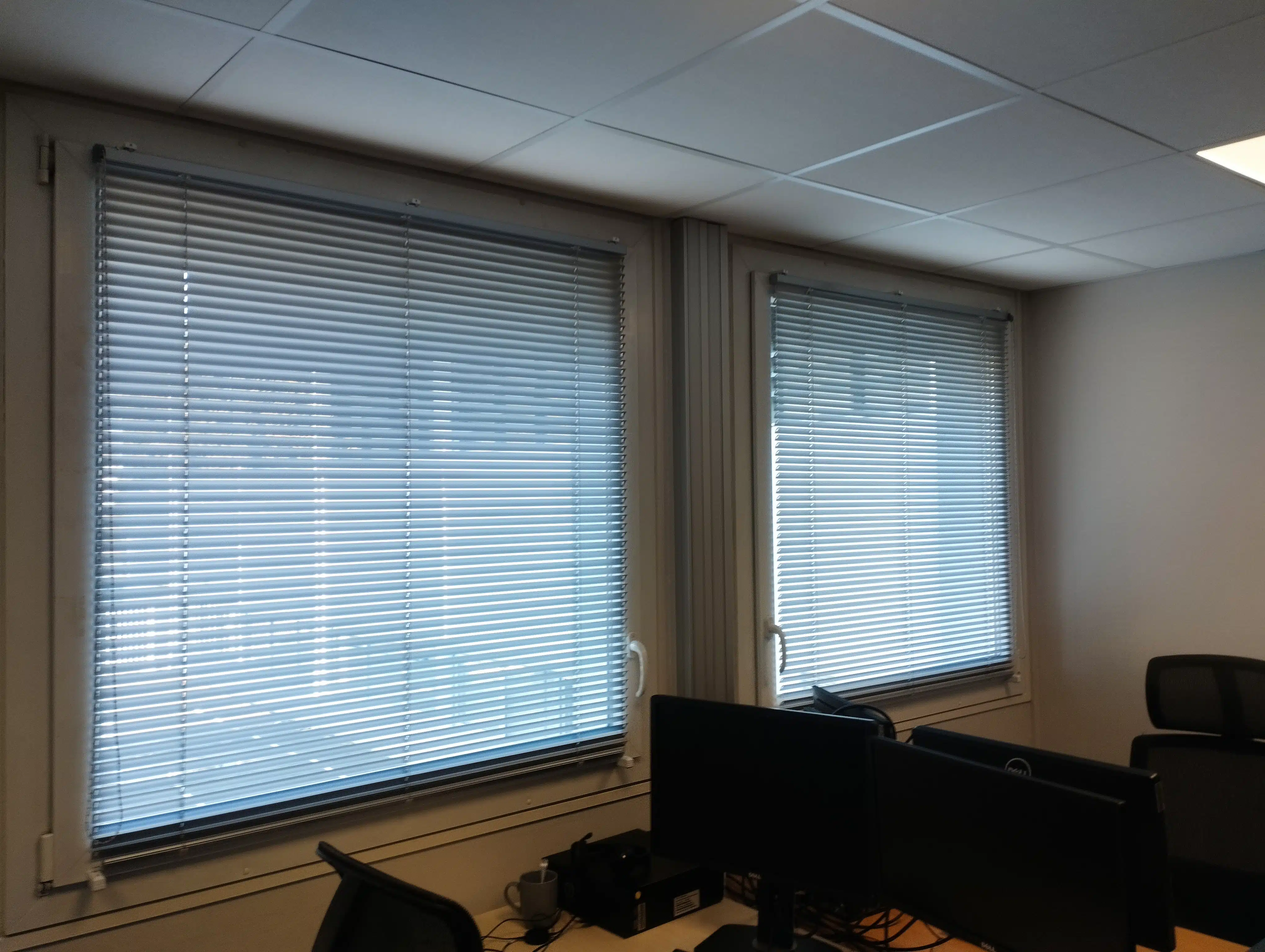 Stores vénitiens en aluminium installés dans un bureau professionnel, gestion de la lumière naturelle