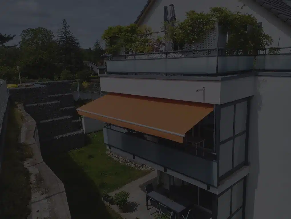 Store banne orange installé sur balcon d’appartement, protection solaire extérieure moderne en Alsace